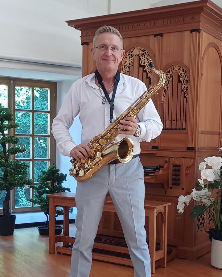 Michael Gilcher mit seinem Tenorsaxofon vor einer Orgel